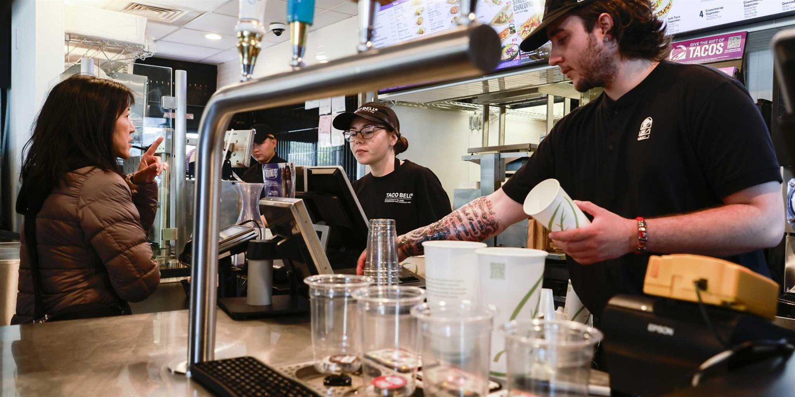 Crew serving a customer at a Taco Bell counter.