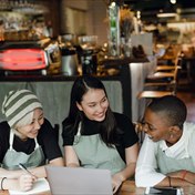 Three staff members working through something together on a laptop.